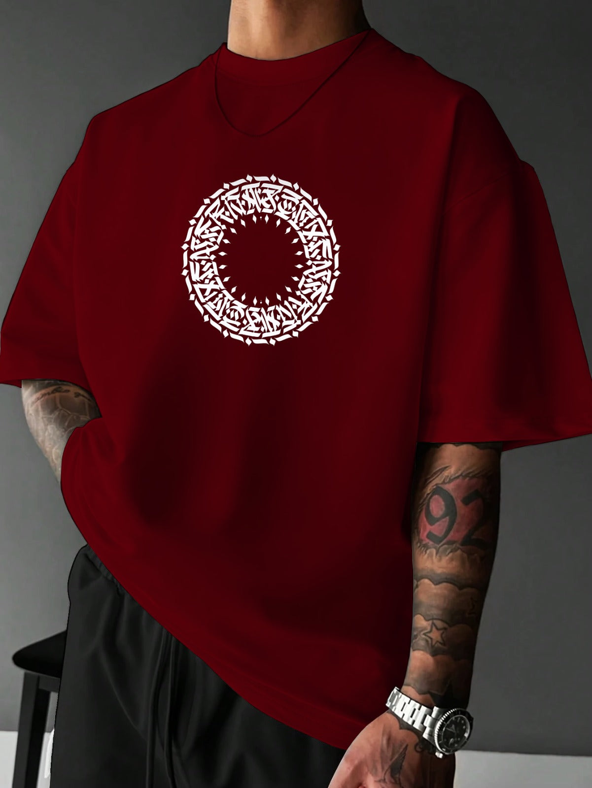 Red t-shirt with a white circular design worn by a person against a gray background