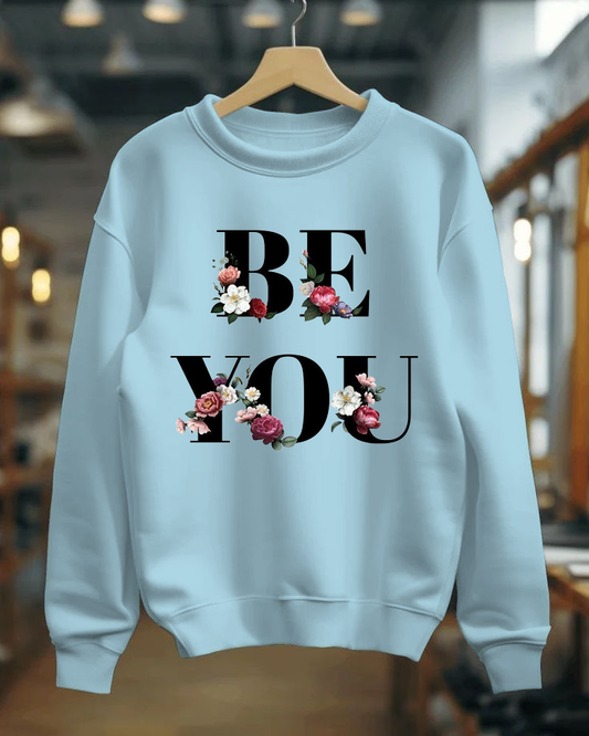 Light blue sweatshirt with 'BE YOU' text and floral designs on a hanger.