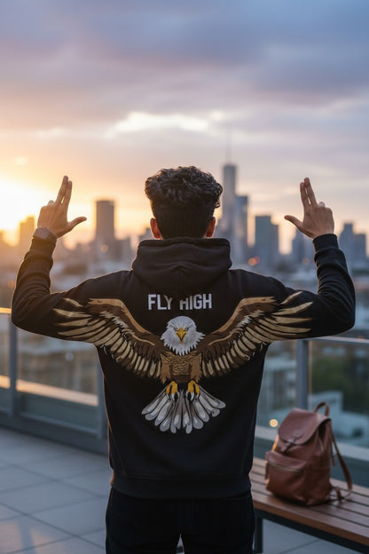 Person wearing a hoodie with an eagle design and 'Fly High' text, standing on a rooftop with a cityscape view.