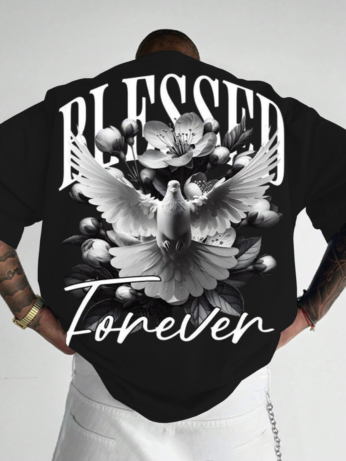 Person wearing a black t-shirt with 'Blessed Forever' design featuring a dove and flowers on a plain background.