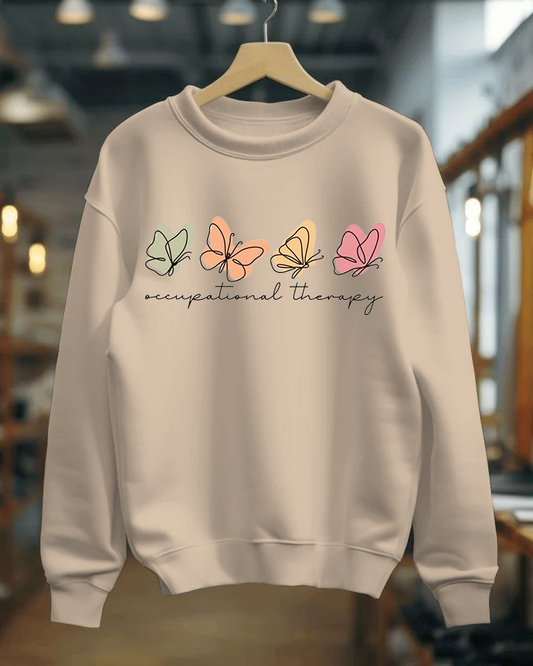Beige sweatshirt with colorful butterfly designs and 'occupational therapy' text on a hanger.