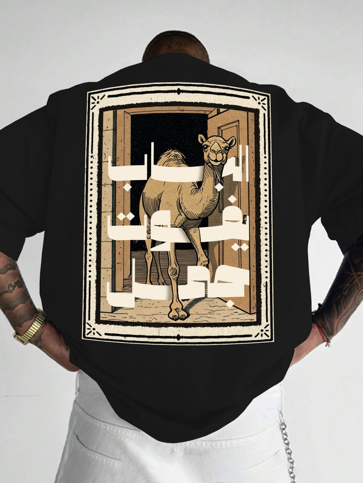 Person wearing a black shirt with a camel design on the back, standing against a white background