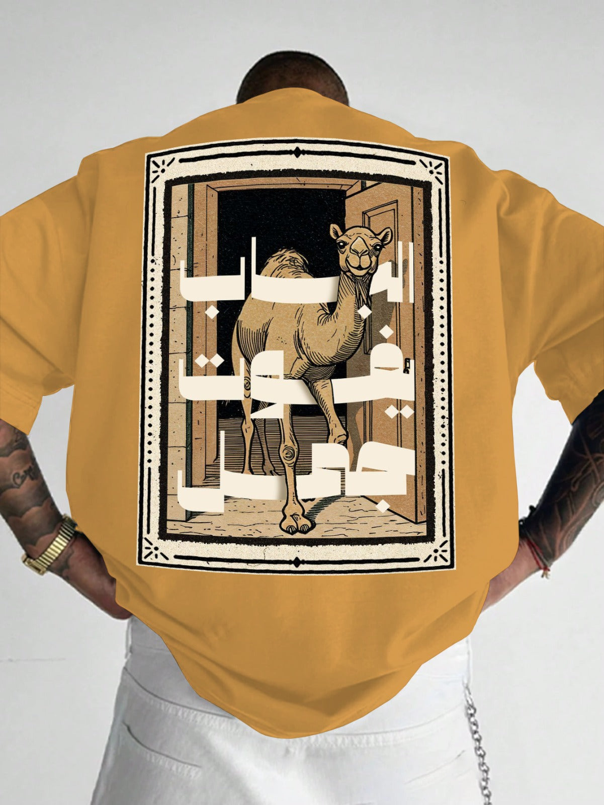Person wearing a mustard yellow shirt with a camel graphic on the back against a white background