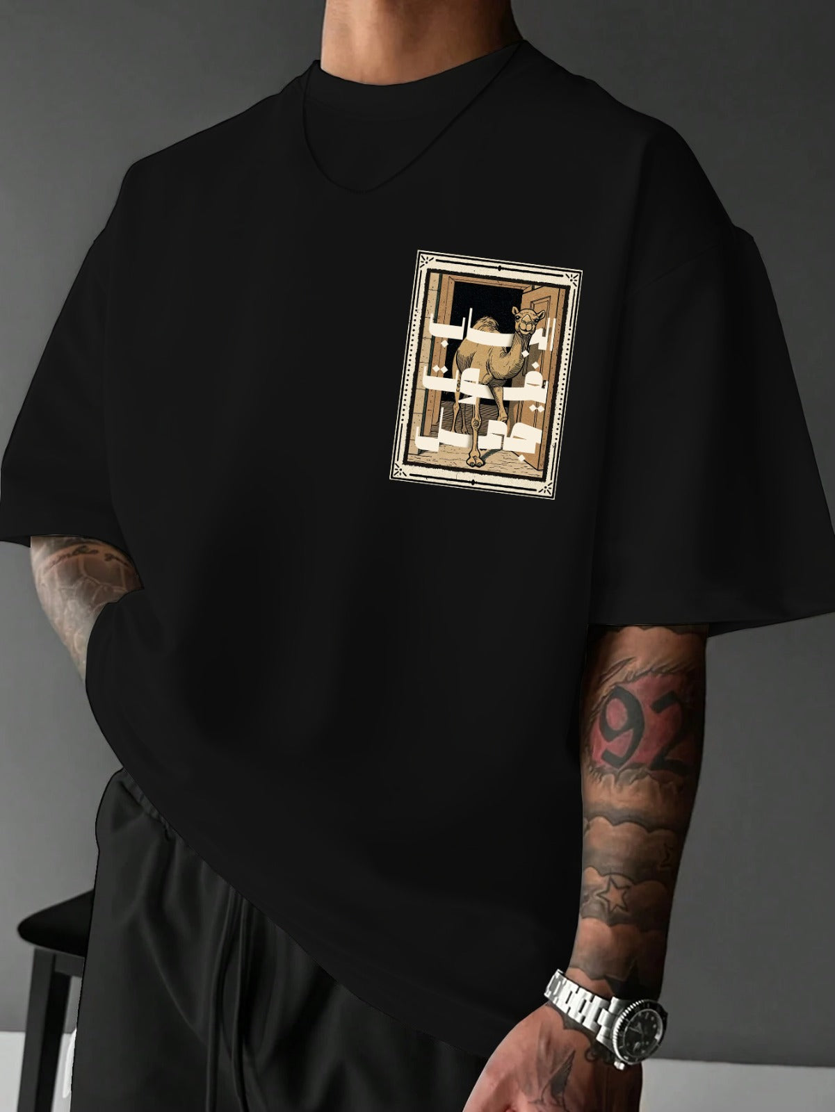 Person wearing a black t-shirt with a graphic design on a gray background