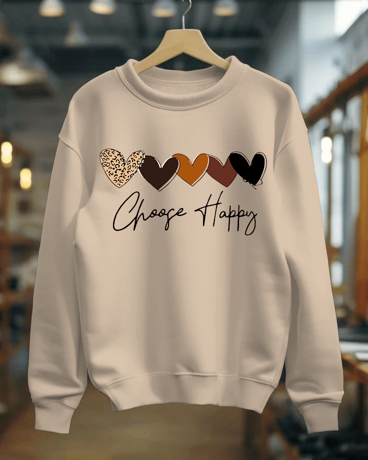 Beige sweatshirt with colorful heart designs and 'Choose Happy' text on a hanger.