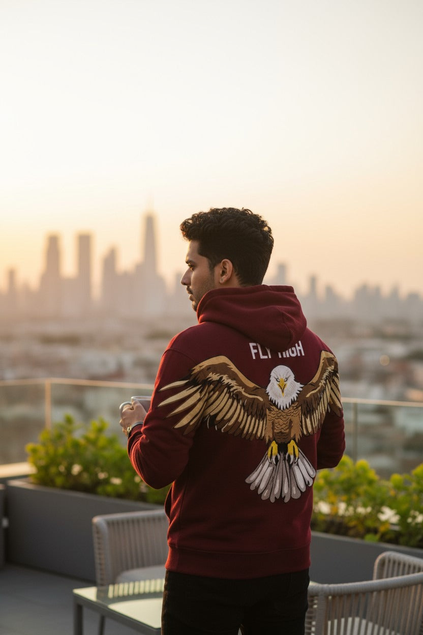 Person wearing a hoodie with an eagle design on a rooftop with a cityscape in the background