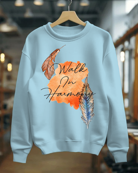 Light blue sweatshirt with feather design and 'Walk In Harmony' text on a hanger.