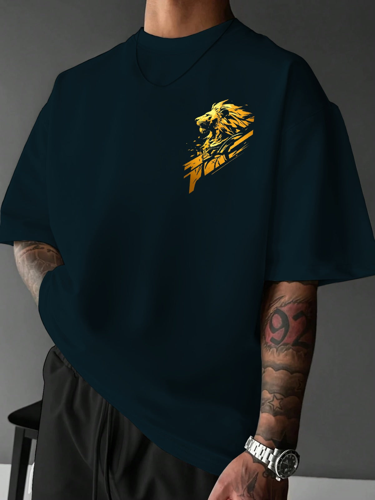 Person wearing a black t-shirt with a yellow lion graphic design on a gray background