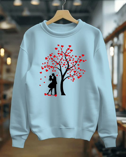 Light blue sweatshirt with a heart tree design on a hanger against a blurred indoor background