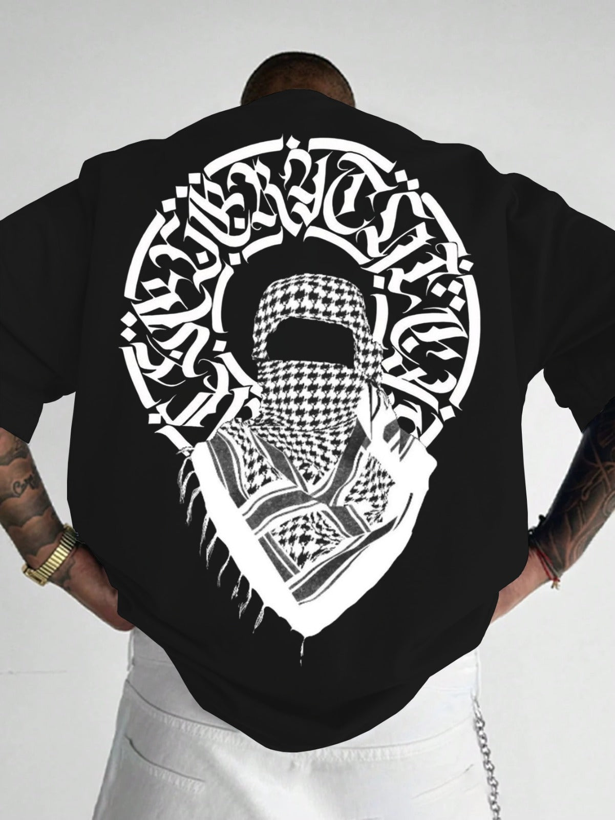 Person wearing a black t-shirt with a white graphic design on the back, featuring Arabic text and a headscarf.