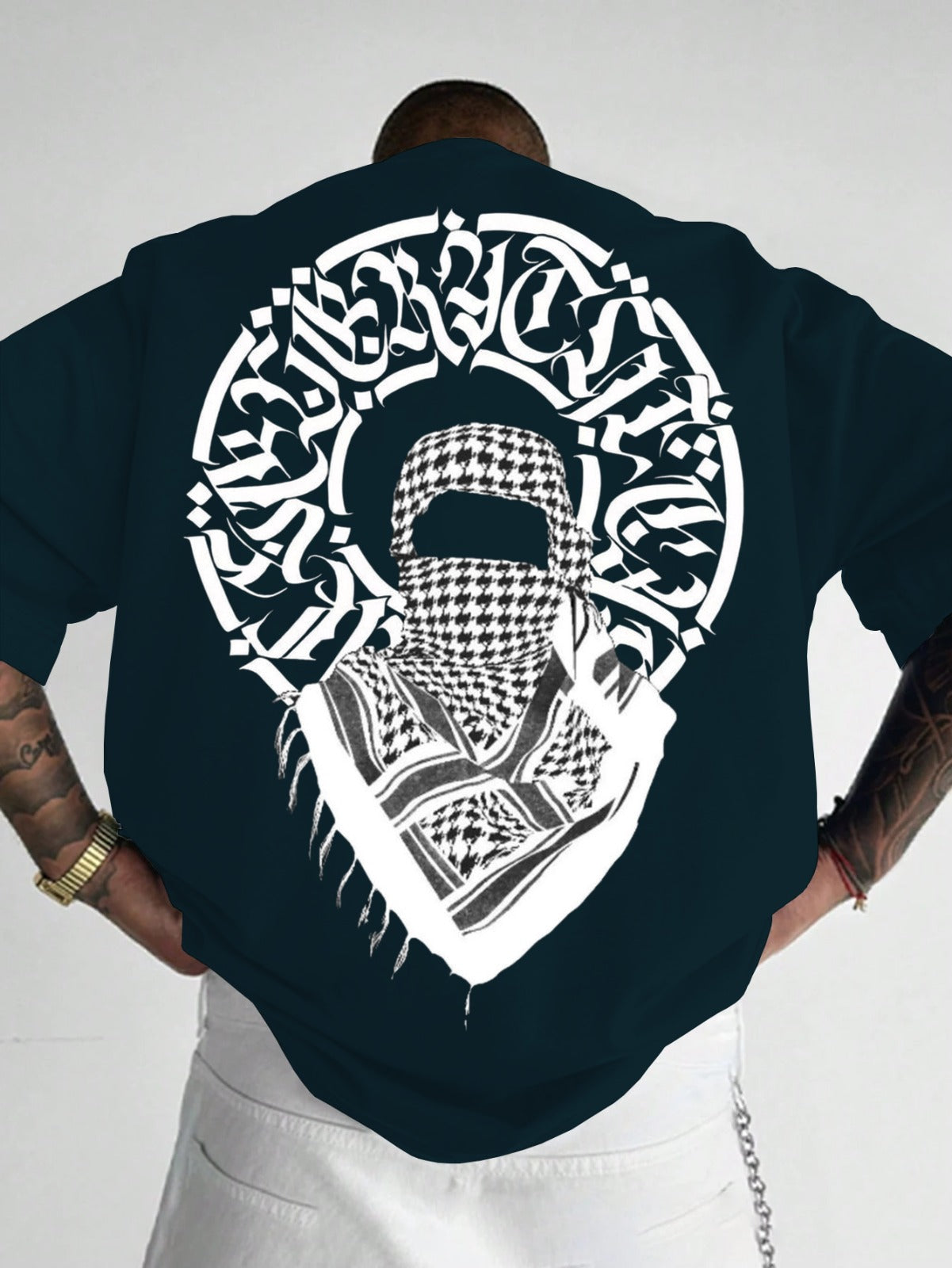 Person wearing a black t-shirt with a white graphic design on the back, featuring a headscarf and Arabic text.