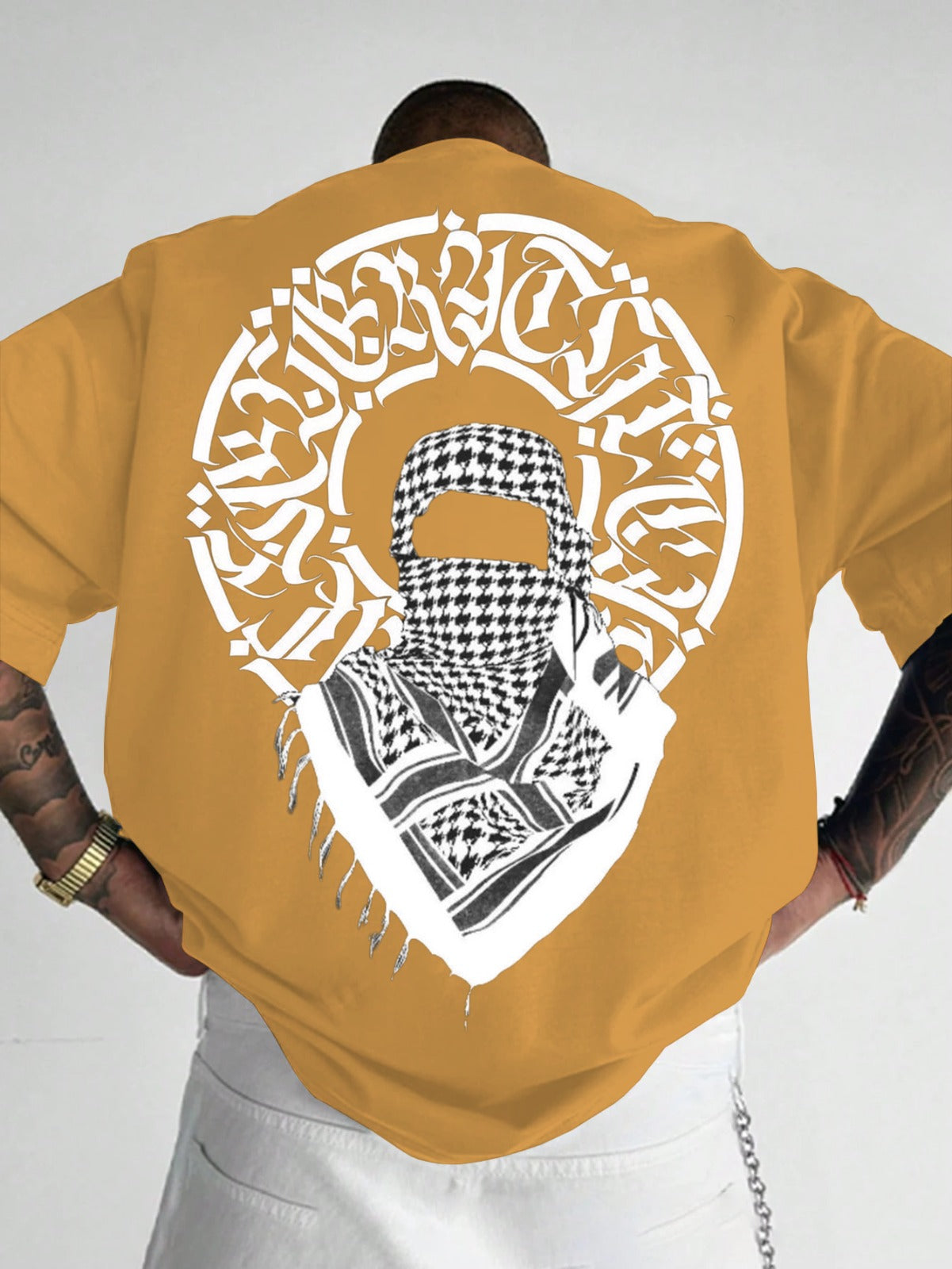 Person wearing a mustard yellow t-shirt with a graphic design on the back.