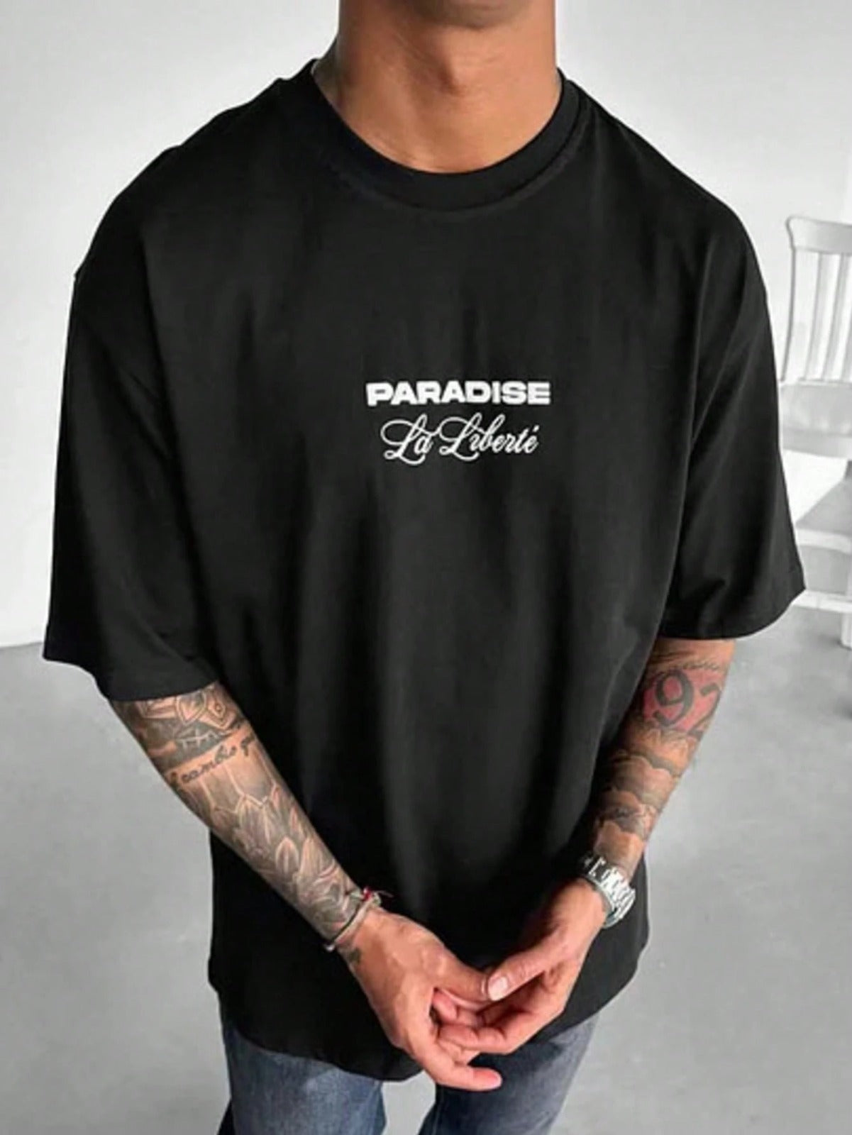 Person wearing a black t-shirt with 'Paradise Libre' text on a plain background