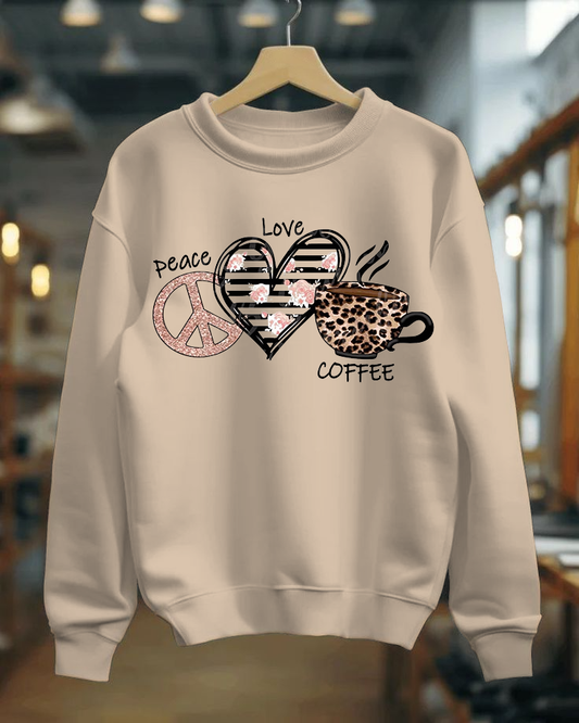 Beige sweatshirt with peace, love, heart, and coffee cup design on a hanger.