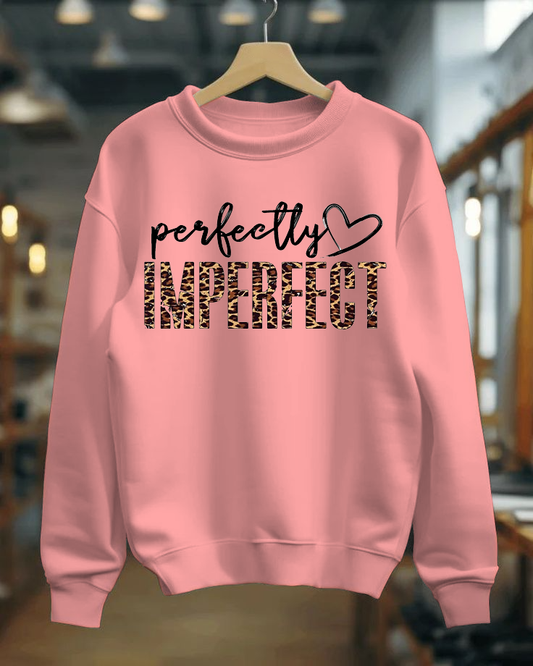 Pink sweatshirt with text on a hanger against a blurred indoor background