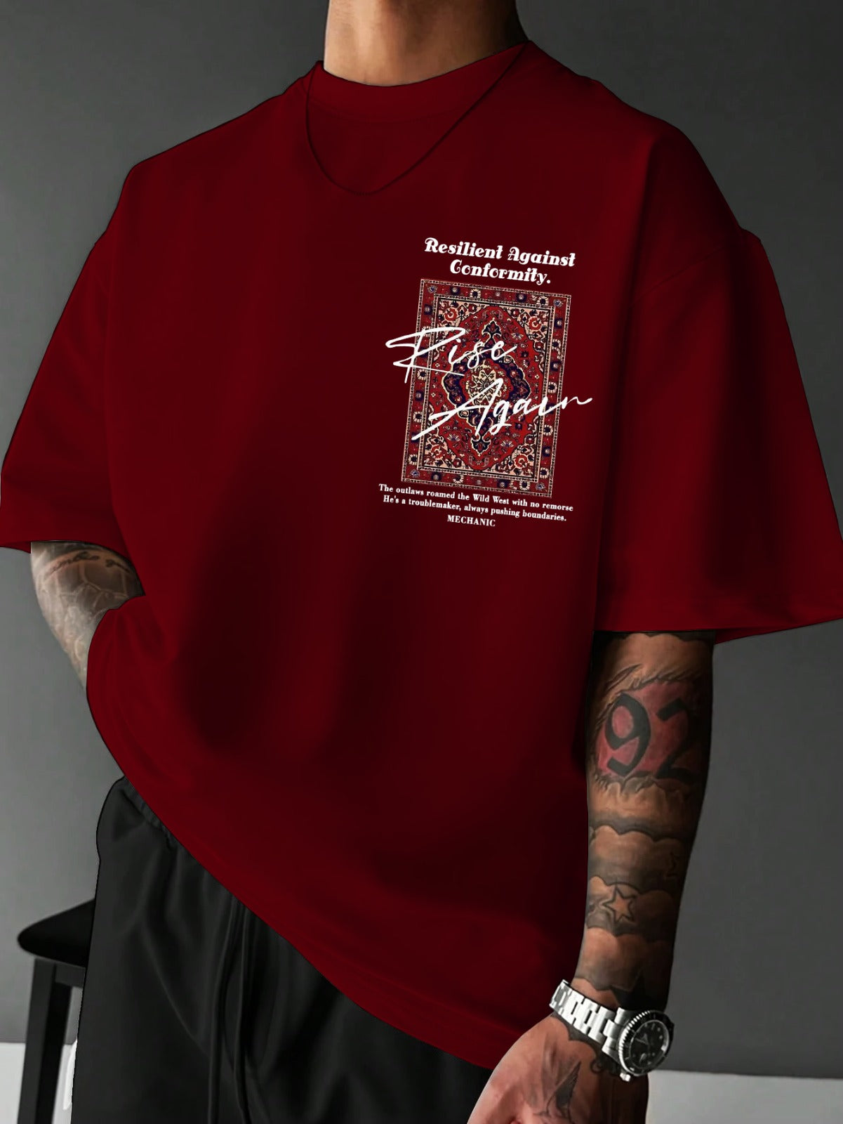 Red t-shirt with graphic design and text worn by a person against a gray background