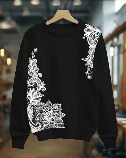 Black sweatshirt with white lace detailing on a hanger against a blurred indoor background